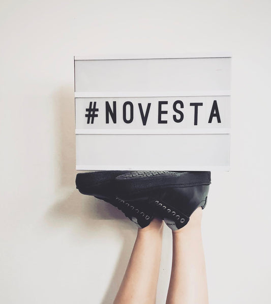 「#NOVESTA」のサインと、手で持ち上げた黒いスニーカー。